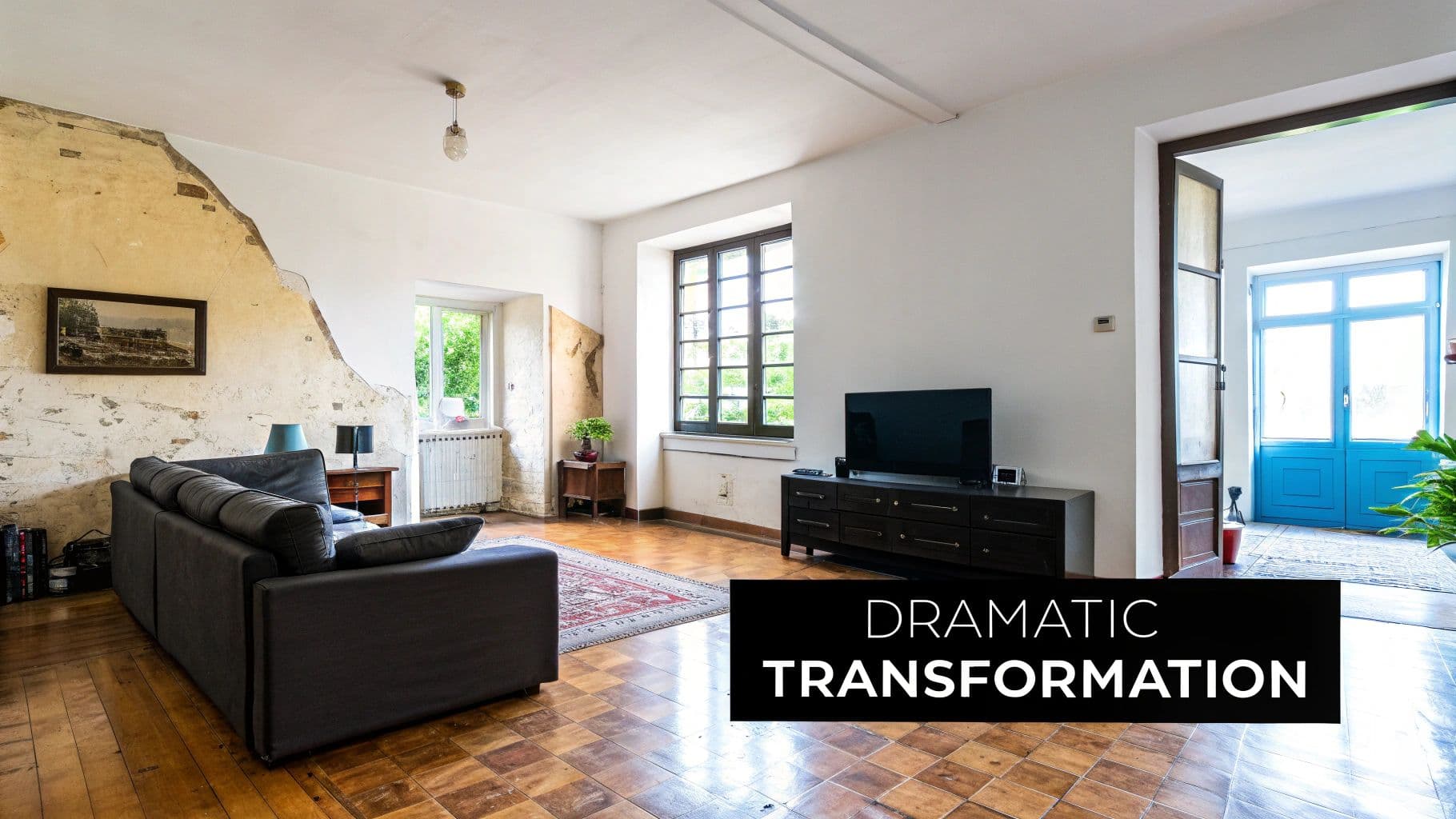 An interior living space with exposed wall, dark sofa, television, and blue doors, indicating a transformation.